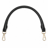 Black leather bag strap with gold hardware on a white background