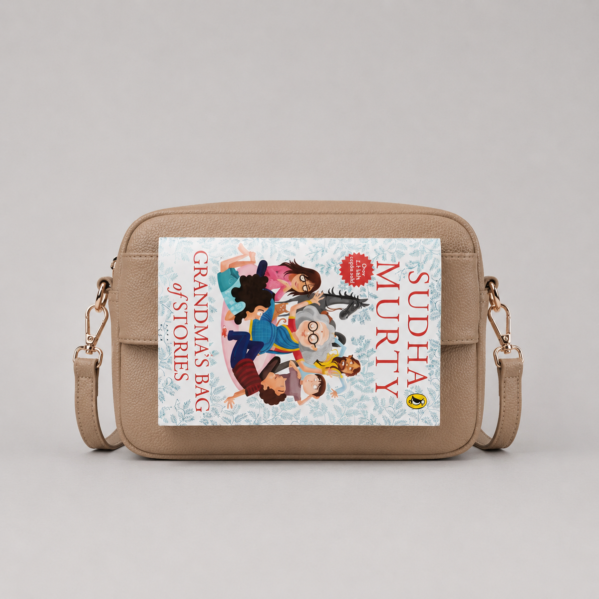 The Daily in Camel bookmark-inspired crossbody bag holding a book