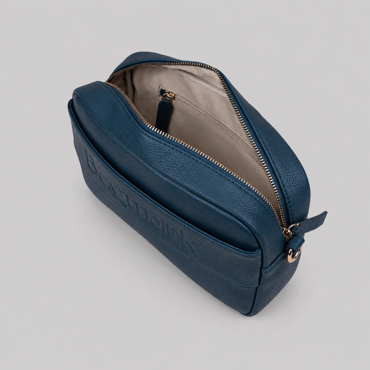 The Daily in Teal bookmark-inspired crossbody bag with gold zipper displaying inner compartments of the bag