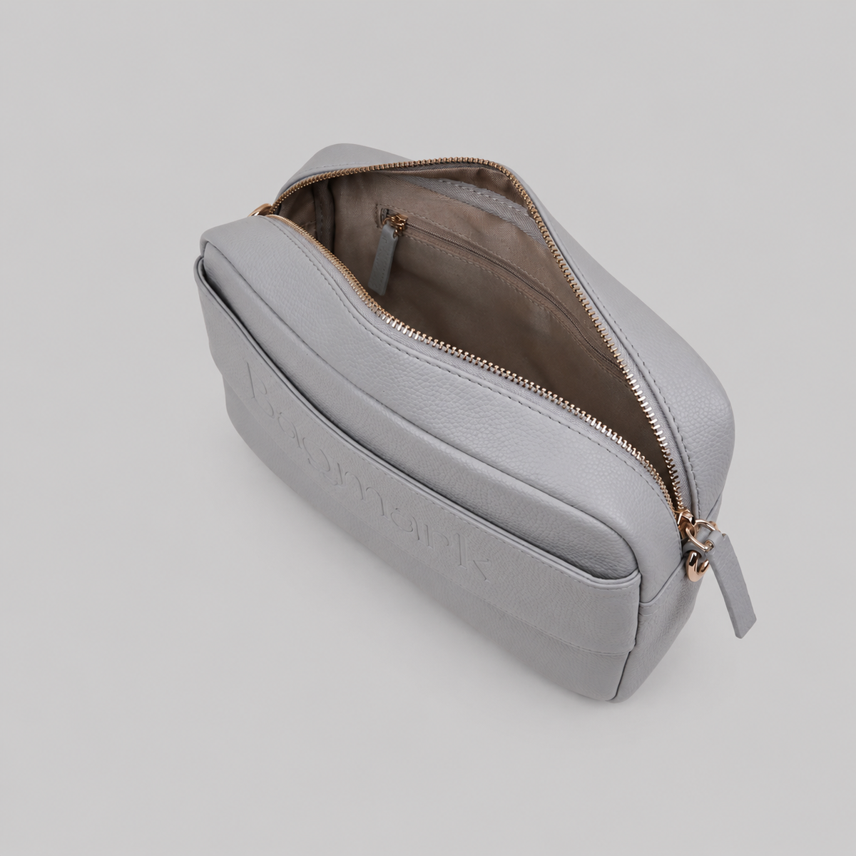 The Daily in Stone bookmark-inspired crossbody bag with gold zipper displaying inner compartments of the bag