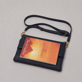 The Essential Navy bookmark-inspired crossbody bag holding a book