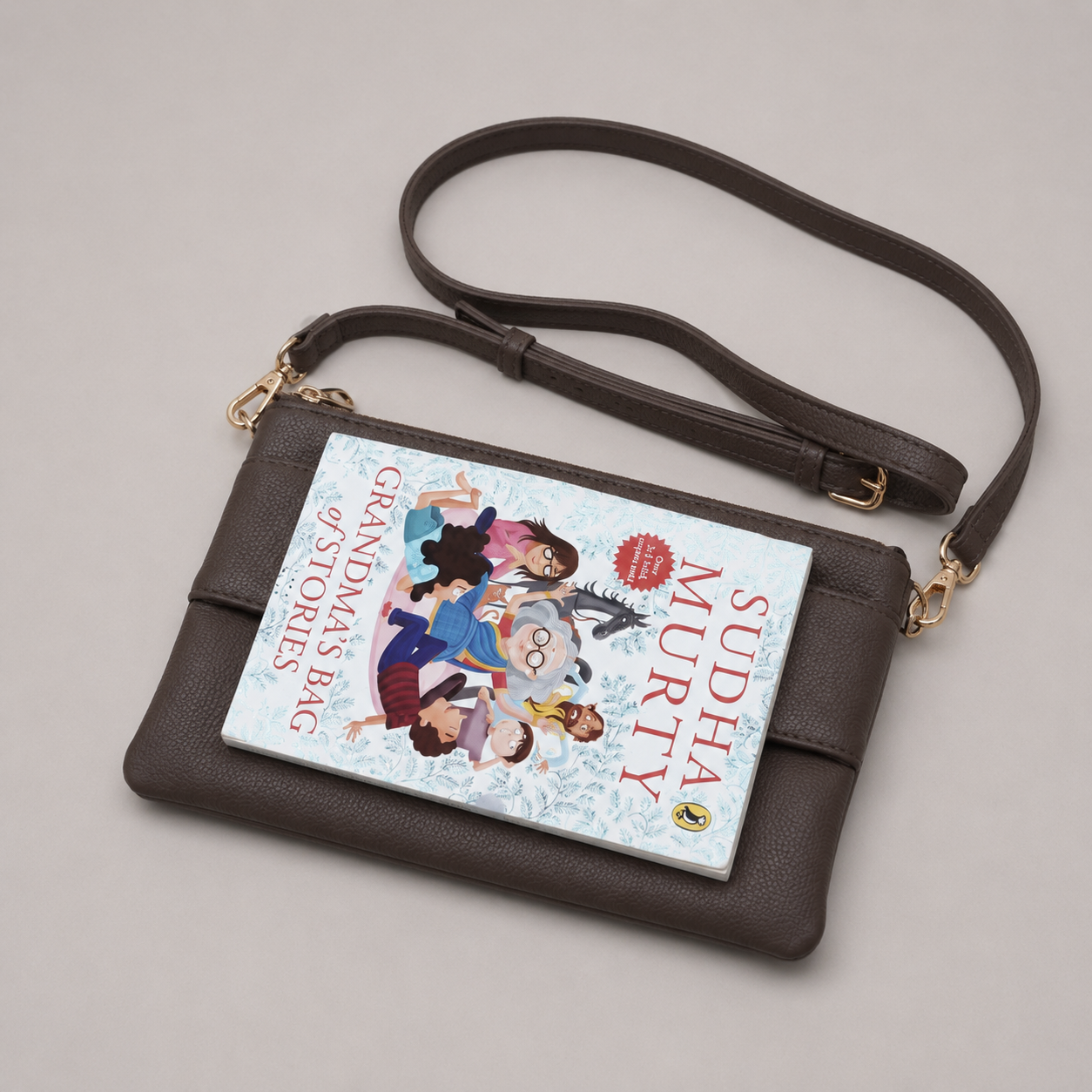 The Essential Taupe Brown bookmark-inspired crossbody bag holding a book