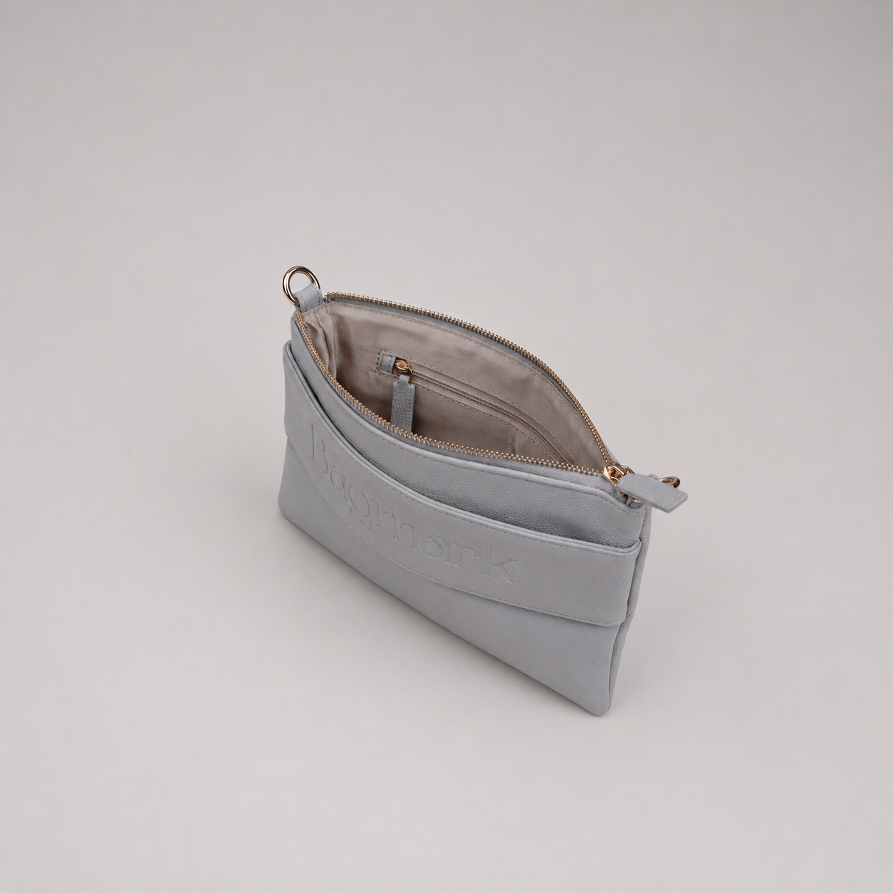 The Essential Stone bookmark-inspired crossbody bag with gold zipper displaying inner compartments of the bag