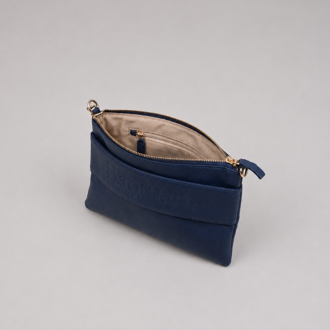 The Essential Navy bookmark-inspired crossbody bag with gold zipper displaying inner compartments of the bag