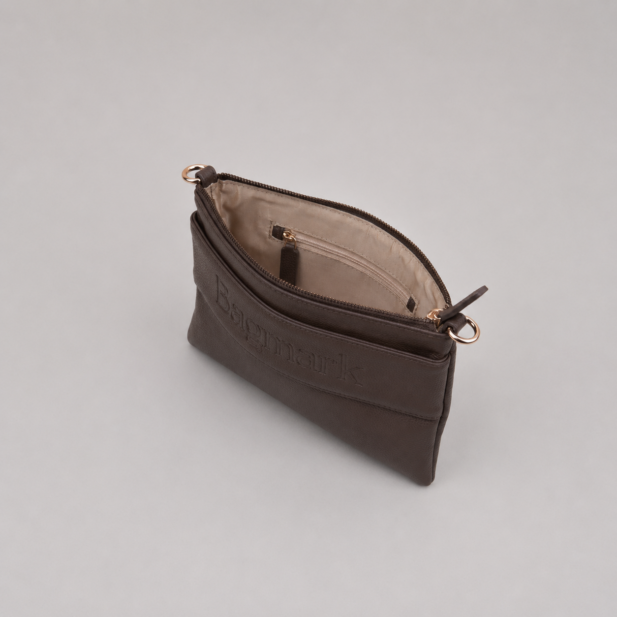 The Essential Taupe Brown bookmark-inspired crossbody bag with gold zipper displaying inner compartments of the bag