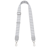 Houndstooth patterned strap with silver hardware on a white background
