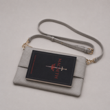 The Essential Stone bookmark-inspired crossbody bag holding a book