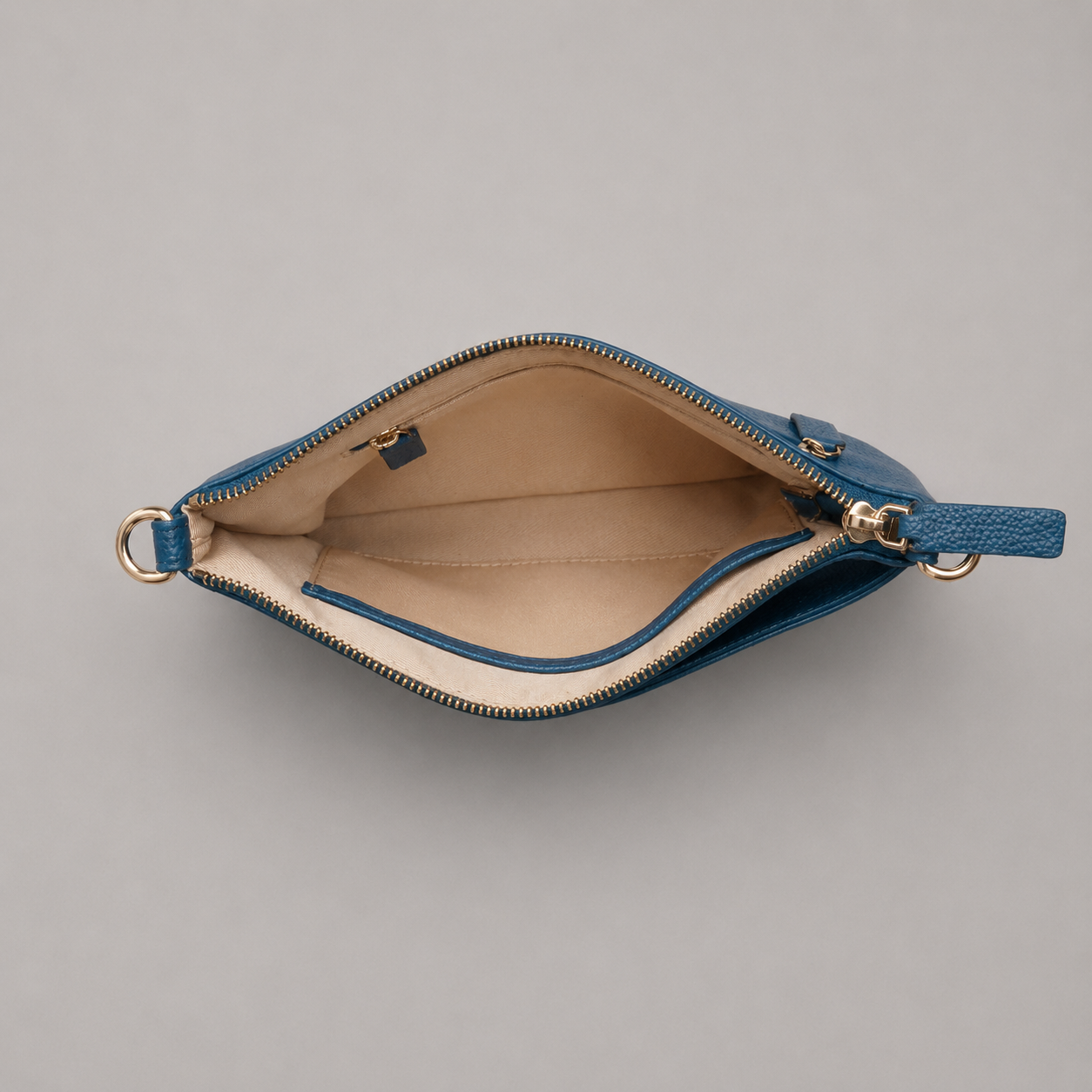 The Essential Teal bookmark-inspired crossbody bag with gold zipper displaying inner compartments of the bag